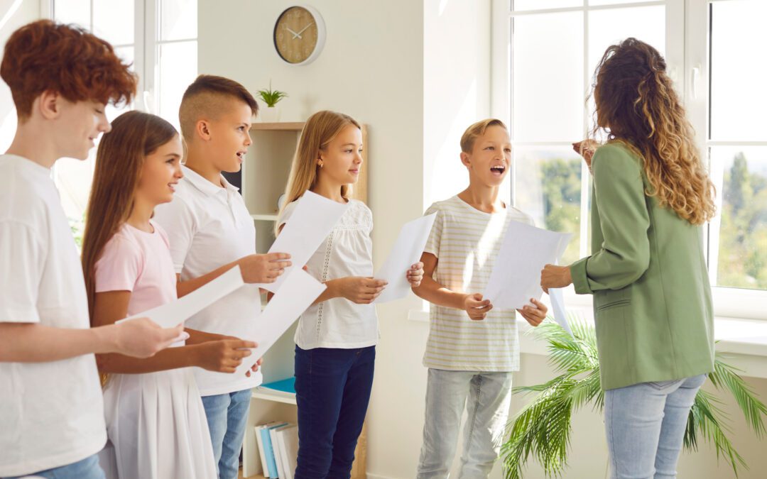 Young school children standing in a circle with their young female teacher having music lesson